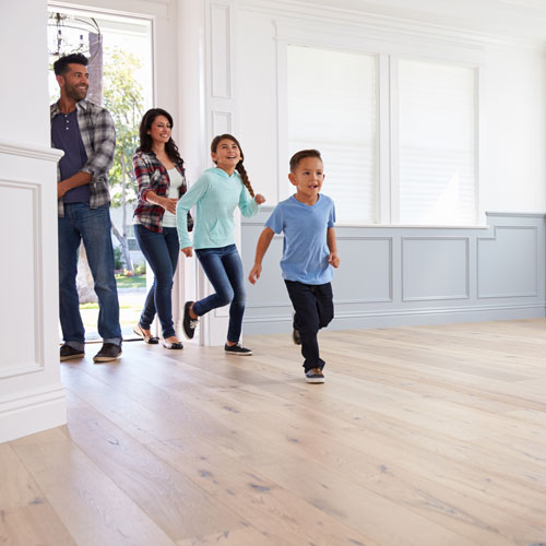 family running into room with light-colored hardwood flooring