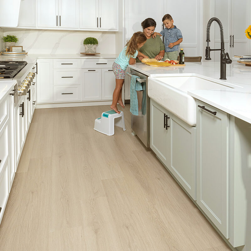 family gathered around a countertop in a kitchen featuring neutral flooring