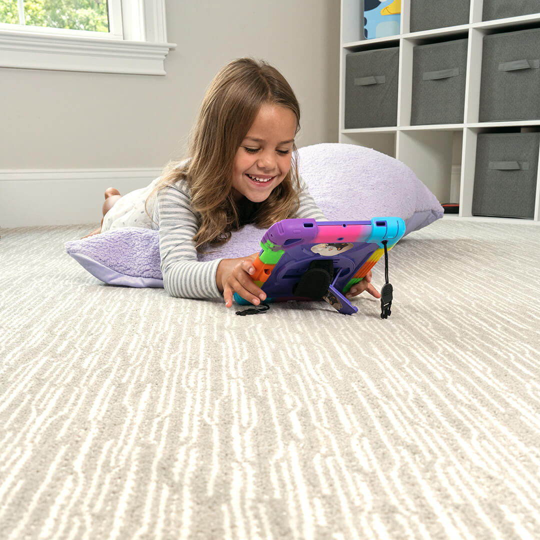 child playing on a device on a carpet floor