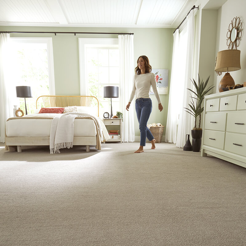 woman walking across neutral carpet in bedroom